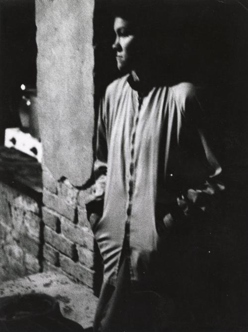 Portrait of figure leaning on brick wall in the dark