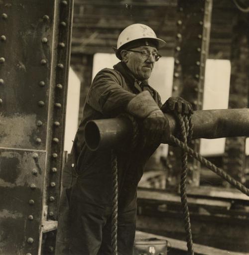 Construction worker tying rope on metal tube