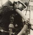 Construction worker in "Bethlehem Steel" hardhat working with heavy pipes with cigarette in mouth