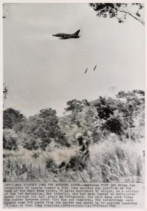Viet Cong The Burning Issue: American F100 jet drops two canisters of napalm toward a Viet Cong machine gun position on the bank of the Rach Beng river, 70 miles northwest of Saigon, as a soldier of the 1st Battalion, 2nd Infantry, who had been landed by helicopter wades through the tall grass in foreground. The Rach Beng here forms the border between South Vietnam and Cambodia. The infantrymen were landed some 400 yards from the border and moved in to capture hundreds of tons of Viet Cong supplies