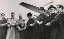A group of clergymen from the Washington area join hands to sing "We Shall Overcome" at Washington National Airport before flying to Alabama to take part in a scheduled march on March 9 for Negro voting rights. The group flew to Montgomery where they planned to take a bus to Selma for the demonstration. Among them are Rabbi Richard A. Hirsch, left, of Washington; Bishop John Wesley Lord, third from left; Methodist Bishop of Washington; and the Rt. Reverend George L. Gringas, second from right, of the Roman Catholic Church.