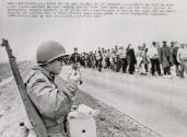 An Army Travels on its Stomach: A soldier, on duty to guard civil rights marchers on their voting protest trek from Selma, Alabama to the state Capital at Montgomery, watches marchers go by as he eats a meal brought to him on the spot. The marchers passing the halfway mark on their 54 mile hike plan to reach Montgomery on Thursday