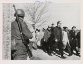 Dr. King Leads Off Second Lap: Dr. Martin Luther King, extreme right, civil rights leader, strides out of camp near Selma, Alabama, as his protest march started its second lap. Next to King is SNCC Chairman John Lewis. A soldier ordered to duty along with several thousand troops to guard the marchers, stands with rifle along the roadside. The marchers are aiming for the State Capitol at Montgomery.