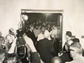 Photo from inside ante-room of Mayor Richard J. Daley's office shows entrance of Congress of Racial Equality demonstrators being barred by police. Garrick Madison (white shirt) 18, spokesman for the group, talks with Col. Jack Reilly (white hair), the mayor's director of special events, who eventually allowed Madison and four other representatives of CORE to enter the suite for an interview with Daley. Daley later told reporters: "They asked for my co-operation with regarding the Board of Education, and I told them it is not my policy to interfere with the Board of Education." Reporters and city hall workers are amidst CORE group outside office, Chicago.