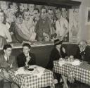 Restaurant interior with customers seated in front of mural