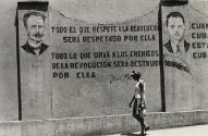 Woman walking past propagandist mural, Santiago de Cuba