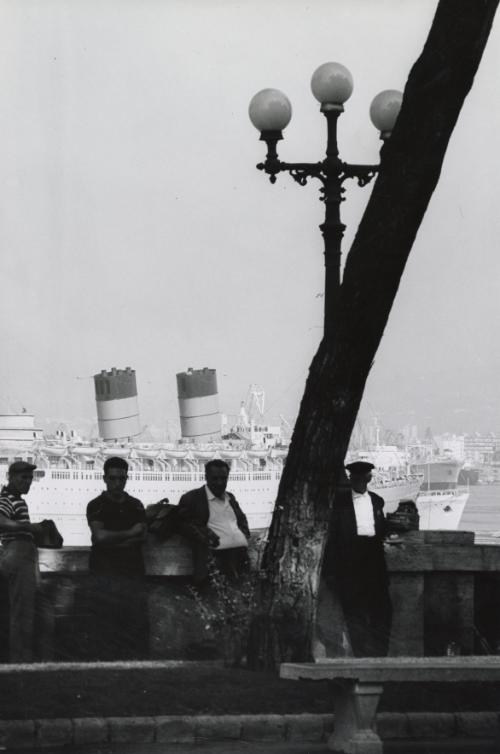 Men leaning on wall with boats in the background, Naples
