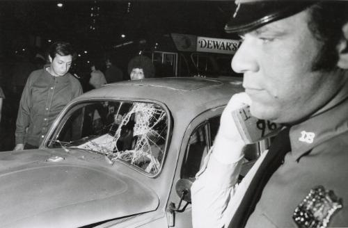 Police officer in front of car with broken windshield, NYC