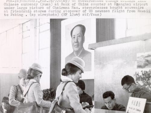 US stewardesses change dollars into Chinese currency (yuan) at Bank of China counter at Shanghai airport under large picture of Chairman Mao. Stewardesses bought souvenirs at friendship stores during stopover of US newsmen flight from Hawaii to Peking