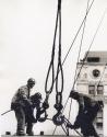 Three construction workers tying topes on crane hooks