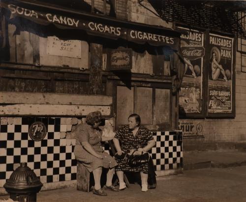 Old women seated outside of stand for sale