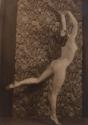 Nude standing in arabesque pose in front of floral wallpaper