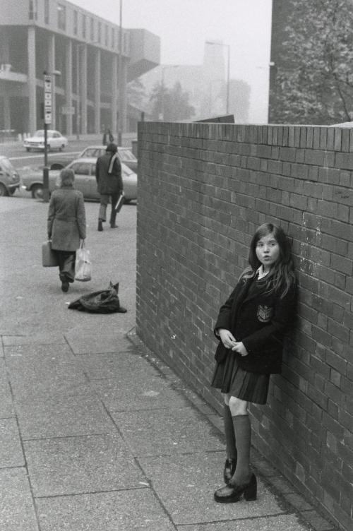 Schoolgirl leaning against brick wall, Manchester, England