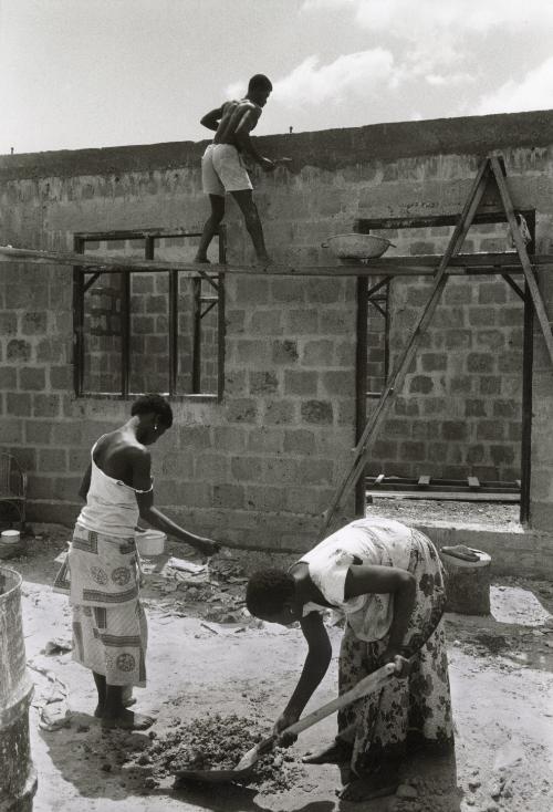 Women digging hole help to construct house, Ghana