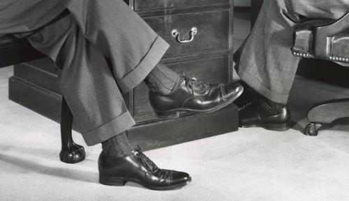 Two men in dress shoes at office desk