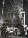 Workers under heavy machinery at steel factory,