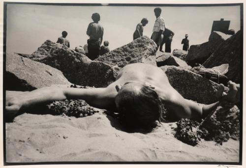 Man lying on the beach between rocks, New York, from the "Hipshot" series.