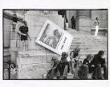 People sitting on museum steps with Max Ernst poster, Paris, France