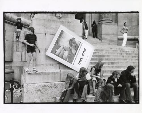 People sitting on museum steps with Max Ernst poster, Paris, France