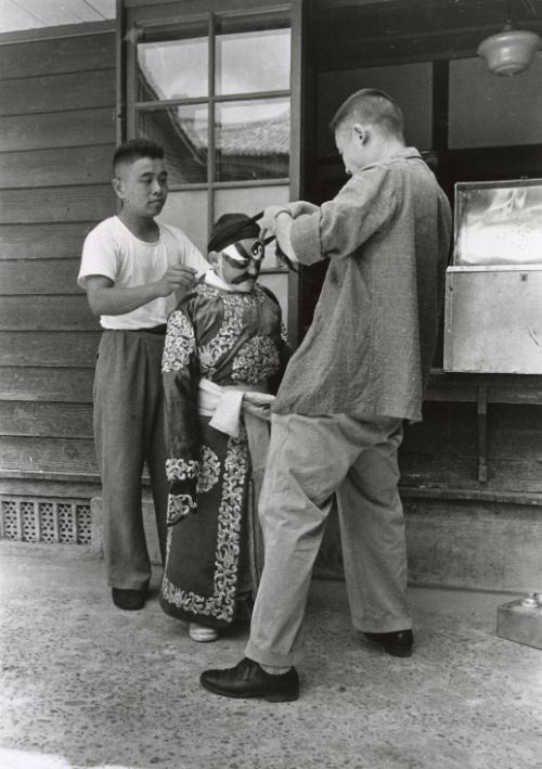 American boy at marital arts school being dressed in traditional costume, Taiwan.
