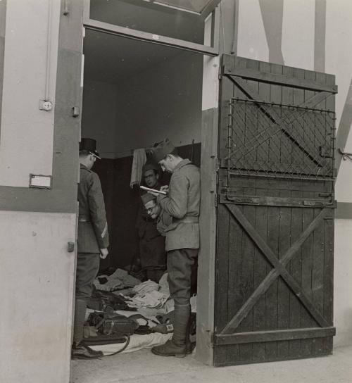 Paris Racing Stables Are Army Quarters: Paris' famous racing stables or Maison-Laritte have be requisitioned by the military authorities and are now quarters for the Army. The premises which used to house famous thoroughbreds of the racetracks are now occupied soldiers who try to make themselves at home as much possible. / The soldiers have to keep their boxes in ship-shape order. Photo shows inspection by an officer in charge of the stable quarters.