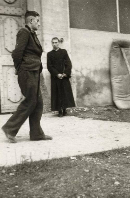 Uniformed man walking past priest