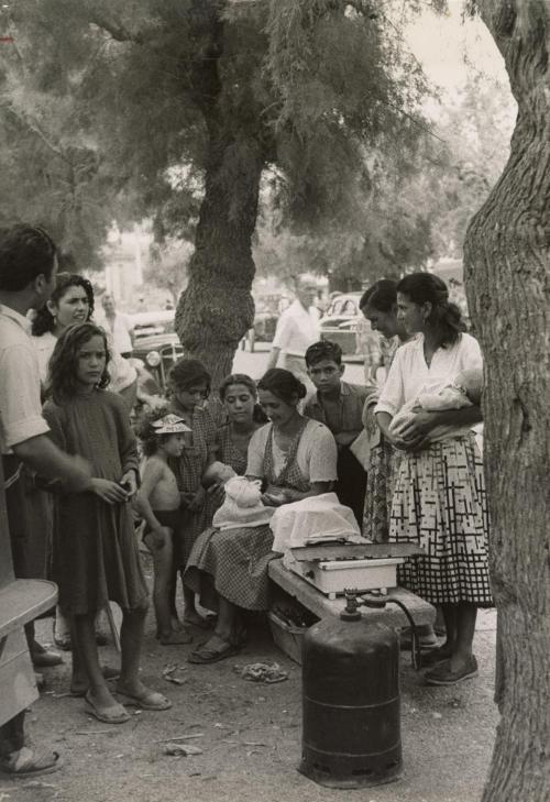 Gypsies gather under a tree to look at a mother's newborn, Saintes Maries de la Mer, France