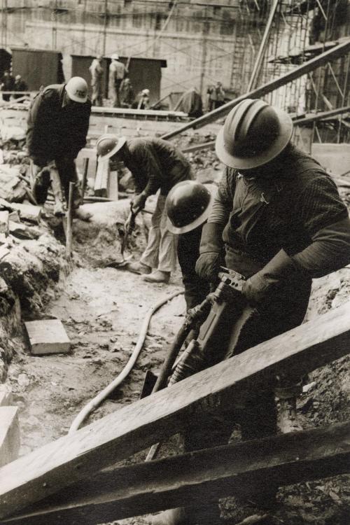 Constructing workers jack-hammering and digging