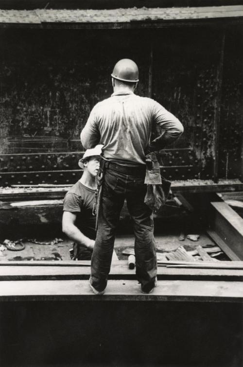 Two construction workers conversing on construction site
