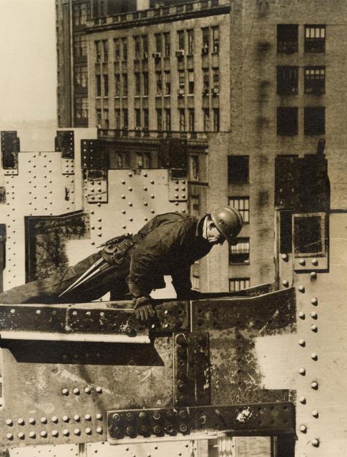 Construction worker climbing over metal beam