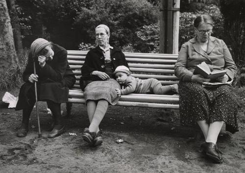 Child lying on a bench while three elderly sitting next to him, Georgia
