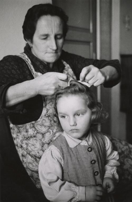 Old woman doing girl's hair