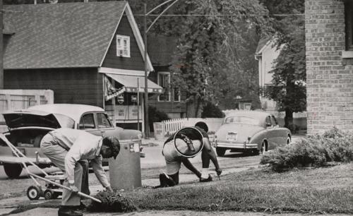 Off-Duty: Chicago policeman William Sherrod (right) wore his service revolver as he helped a friend, the Reverend Edward Dixon, cut grass in front of his home in a white neighborhood. Mr. Dixon, a Cook County Hospital chaplain, recently purchased the house.