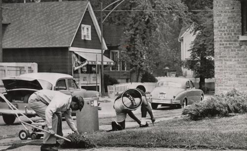 Off-Duty: Chicago policeman William Sherrod (right) wore his service revolver as he helped a friend, the Reverend Edward Dixon, cut grass in front of his home in a white neighborhood. Mr. Dixon, a Cook County Hospital chaplain, recently purchased the house.