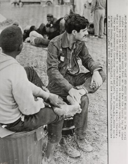 Weary and Muddy But More to Go: two civil rights marchers rest with muddy feet as they face the fourth lap of their protest march on the Alabama state capitol at Montgomery today. They have nearly half of the distance to cover before reaching the capitol Thursday. They are 14-year-old Cornelius Courtland, left, of Selma, where march started Sunday, and Bruce Hartford, 21, of New Haven.