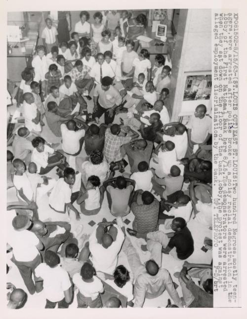 Two hundred Negroes, mostly teenagers, were arrested after police broke up a noisy racial demonstration in the lobby of the First National Bank. The demonstrators were arrested when they sat down on the floor of the bank lobby. The protest was against alleged employment discrimination by the bank, East St. Louis, Illinois.
