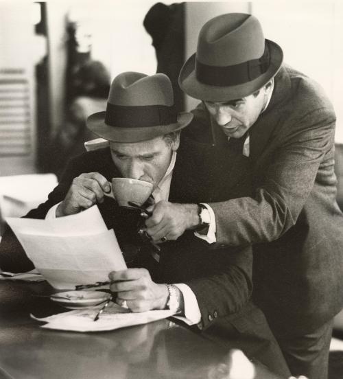 Men looking at paper holding coffee mug and glasses