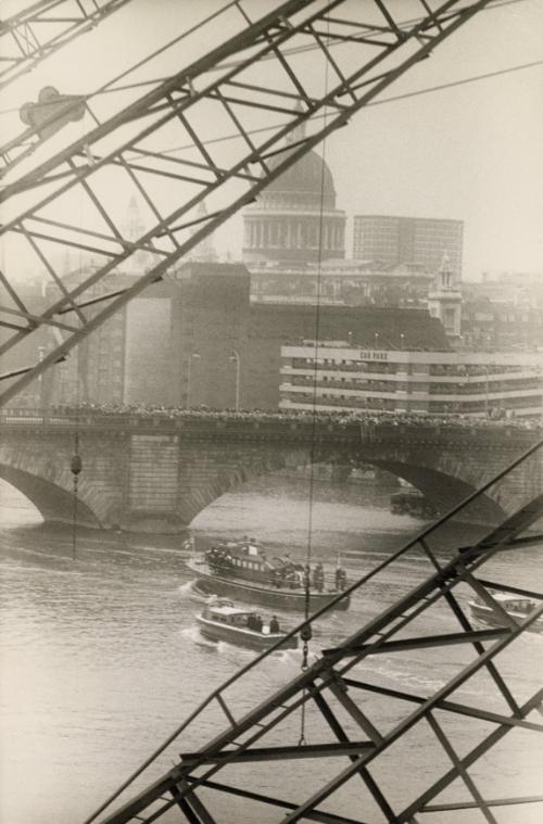 Churchill funeral: Funeral for Winston Churchill. Gantry cranes tip in salute as a barge carries Churchill's coffin on the Thames. Wren Church and the dome of St. Paul's Cathedral are in the background, London, January 29, 1965