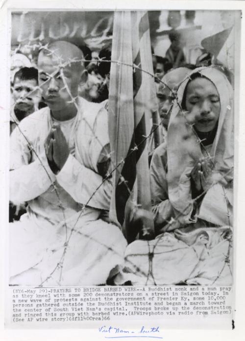 Prayers to Bridge Barbed Wire: a Buddhist monk and a nun pray as they kneel with some 200 demonstrators on a street in Saigon today. In a new wave of protests against the government of Premier Ky, some 10,000 persons gathered outside the Buddhist Institute and began a march toward the center of South Vietnam?s capital. Troops broke up the demonstration and ringed this group with barbed wire
