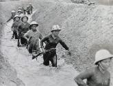 Outside a village, men and women soldiers on maneuvers slogged through the water of an irrigation ditch