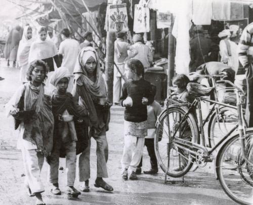 Sikh children in Amritsar walk through a market place of the city seeking food. They carry their bowls with them to take advantage of anyone's generosity, India