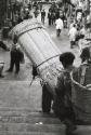 Boys carrying a basket and rug down stairs on their backs, Syria