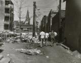 Men walking down trash covered street