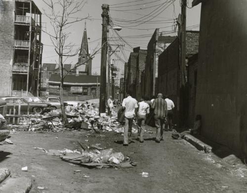 Men walking down trash covered street