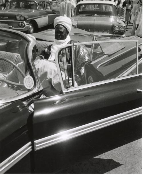 Nigeria, “The Sardonna, Premier of the Northern Region is shown in one of his cars, this being a new Chevrolet with a musical horn.”