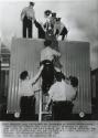 Police Use Stretcher to Remove Demonstrator: Woman who had climbed atop roof of mobile classroom is removed down ladder by police who have encased her in a canvas stretcher bag. Only her face protrudes. She was identified as Janet Heywood, 20, of Chicago. Many other demonstrators were arrested as pickets continued to protest that the mobile units serve to maintain 'de facto' segregation. Demonstrators claim that Negro students in overcrowded schools should be sent to white schools, Chicago.