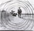 A South Vietnamese militiaman is framed in a coil of razor wire, similar to barbed wire, at an outpost near Cu Chui in the Saigon region. Military patrols have continued in the post cease-fire days.