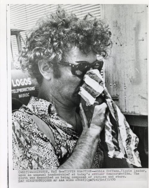 Yippie Reaction: Abbie Hoffman, Yippie leader, uses an unusual handkerchief at today's antiwar demonstration. The cloth was described as being composed of stripes and stars.