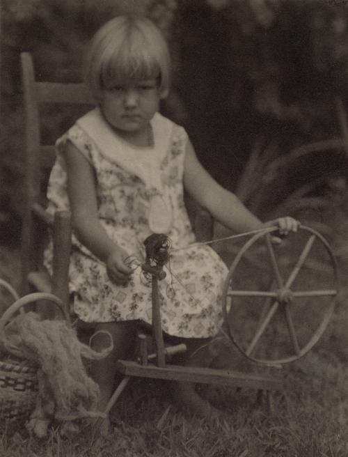 Portrait of seated girl spinning wool