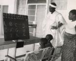 Family at home teaching their children the alphabet, likely Dakar, Senegal, Africa, 1959